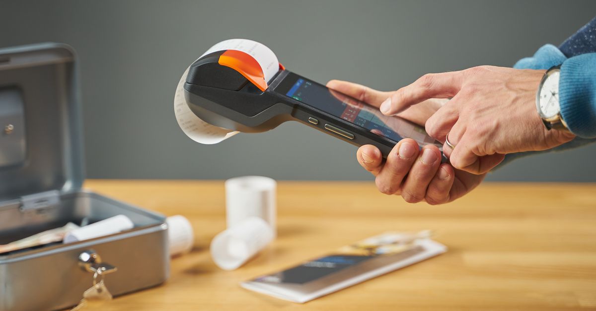 Mano sosteniendo un teléfono para fotografiar un comprobante sobre la mesa