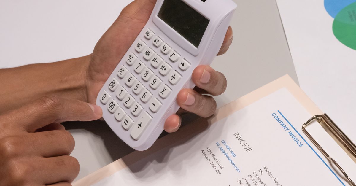 Facturas en papel apiladas junto a una calculadora sobre el escritorio